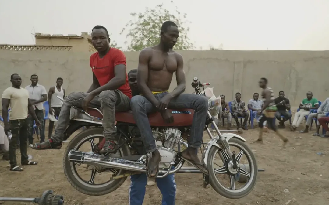 Two men on bike wile man carries bike